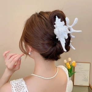 Detail showing creamy white seashell hair claw clip styled on back of head with pearls