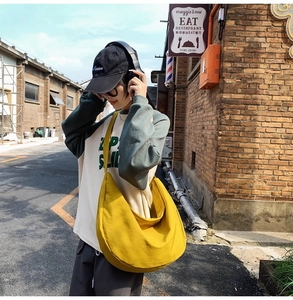 Detailed view of yellow crescent oxford cloth bag on shoulder with wide strap