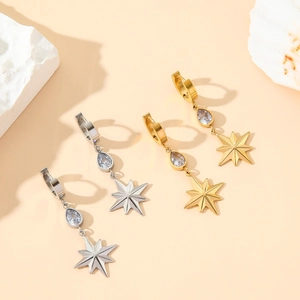 Gold and silver star drop earrings with sparkling zircon stones on warm beige background