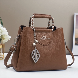 Detailed view of dark brown litchi pattern leather bag with silver chain and leaf pendant