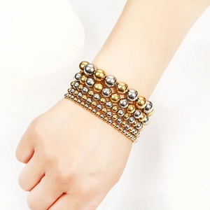 Close-up of mixed gold and silver stainless steel beaded bracelets on wrist