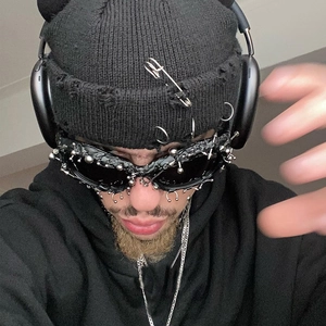 Detail of punk style sunglasses with metal studs and rings on a black knit beanie