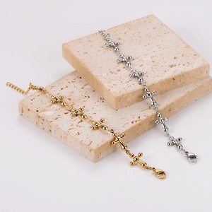 Elegant gold and silver stainless steel cross bracelets displayed on beige stone plates
