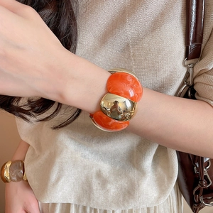 Close-up of chunky marble resin and gold metal link bracelet on a woman wrist