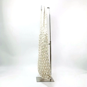 Detail view of the white woven cotton rope handbag side profile hanging on a stand