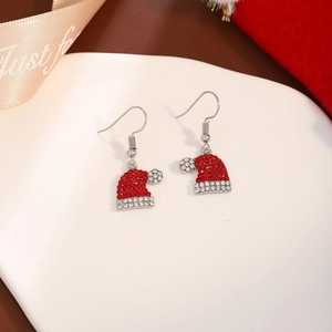 Detailed view of red and silver Christmas hat earrings with shiny rhinestones on a plate