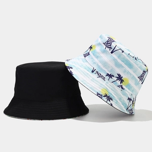 Détail d'un chapeau réversible avec face noire et imprimé de plage avec des palmiers