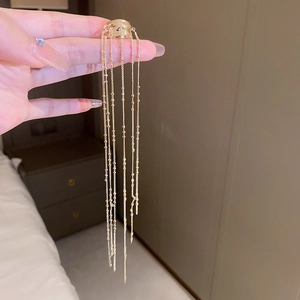 Detailed view of long gold tassel earrings with delicate hanging metal chains