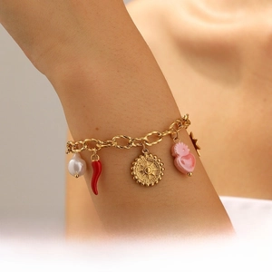 Gros plan du bracelet breloques plaqué or avec pendentif soleil au poignet d'une femme