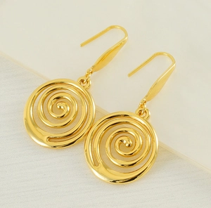 Detailed close-up of golden spiral swirl earrings with high-polished metal finish