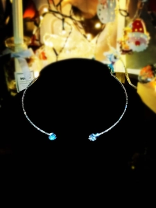 Macro detail of silver choker necklace featuring pavé diamonds and dual blue zircon stones