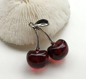 Macro shot of transparent deep red cherry pendant with silver metal leaf details
