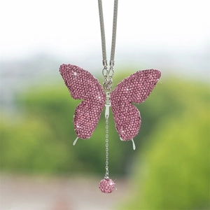 Macro detail of a sparkling pink rhinestone butterfly car charm with matching crystal ball