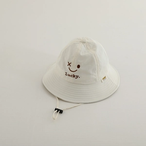 Close-up of white sun hat with brown smiley face embroidery and adjustable windproof cord