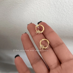 Detail of gold hoop earrings with three zircon-encrusted rings on a hand model