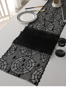Detailed close-up of Halloween black lace spider web runner on a festive dining table