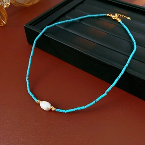 Detail of blue tube bead necklace with a white freshwater pearl and gold lobster clasp