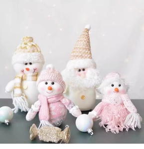 Detailed view of pink and gold Christmas plush dolls with knit hats and sequin accents