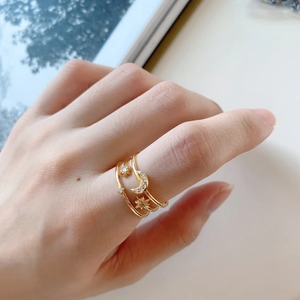 Detailed view of layered gold star and moon open ring with zircon on woman hand