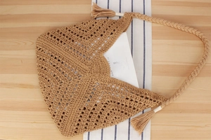 Macro shot of handmade hollow crochet shoulder bag with tassel and magazine detail