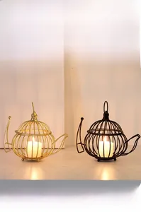 Macro view of creative metal teapot-shaped candle holders in matte black and gold finishes