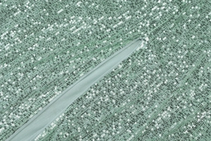 Close-up of green sequin fabric texture and hidden zipper detail on a slim-fit dress