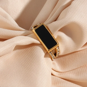 Golden stainless steel ring with black rectangle inlay and side zircon accents on silk