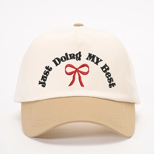 Close-up of contrast color baseball cap with Just Doing MY Best embroidery and red bow