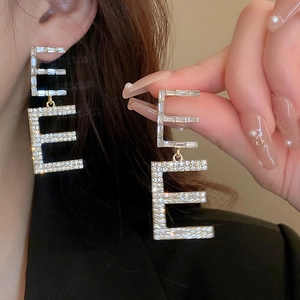 Close-up of oversized letter E earrings with micro-pave cubic zirconia on a silver base