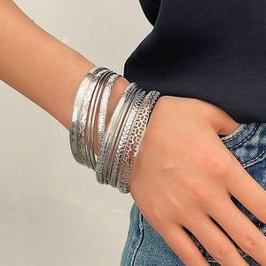 Macro detail of textured silver bangles set featuring honeycomb and hammered patterns