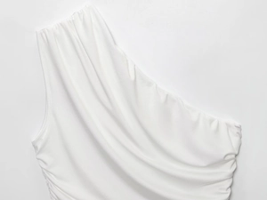 Detail view of white one-shoulder top showing soft textured fabric and elastic pleats