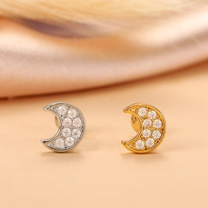 Close-up of gold and silver moon cartilage studs with shimmering zircon inlay detail
