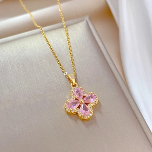 Detailed close-up of a gold clover necklace with pink petals and micro-pave crystals