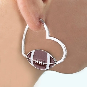 Silver heart hoop earrings with brown rugby ball pendant shown on a female model