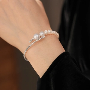 Detailed view of an open silver cuff bracelet with pearls and pavé set diamonds