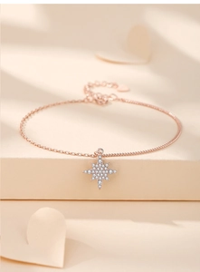 Detail of rose gold star pendant with white zircon stones on a delicate chain