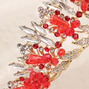 Macro detail of gold bridal crown with red and clear crystals in floral leaf patterns