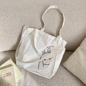 Detalle del bolso tote de lona blanca con lindo estampado de conejo y correa ajustable