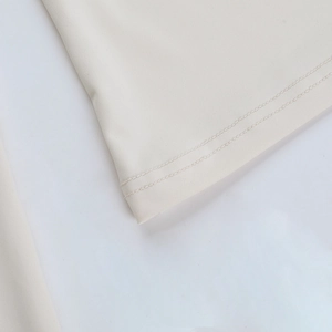 Détail macro de la double couture à l'ourlet sur le haut de sport à manches longues crème