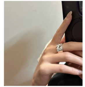 Macro view of wide silver ring with liquid texture and star pattern on finger