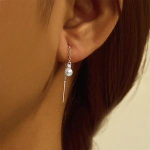 Close-up of 925 silver tassel earring with pearl and zircon on model ear
