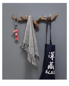 Close-up of vintage brown antler wall hook showing keys and apron hanging on a grey wall