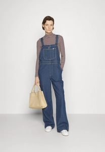 Detailed view of blue denim overalls with cargo pockets and white striped long sleeve top