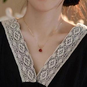 Elegante collana d'oro con un ciondolo di perla di corniola rosso scuro su una modella