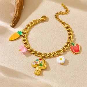 Gold chain bracelet with colorful vegetable and flower charms on a warm textured base