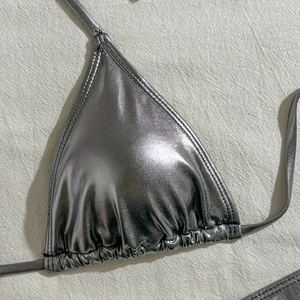 Detail view of silver metallic triangle bikini top with drawstring pleats and mirror finish