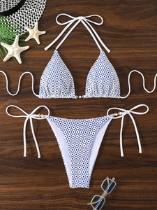 Flat lay of white bikini with blue dots, pearl details and starfish on wooden background
