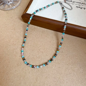 Close-up of bohemian beaded necklace with turquoise and brown beads on a wooden background