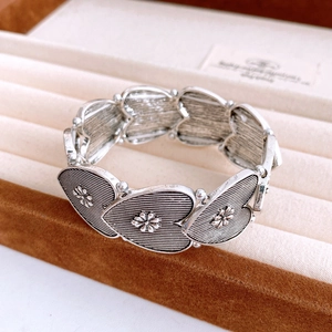 Detailed macro view of vintage silver heart-shaped bracelet links with embossed flowers