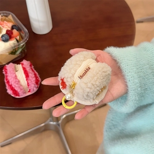 Close-up of off-white plush macaron coin pouch with pearl charm and smooth zipper detail